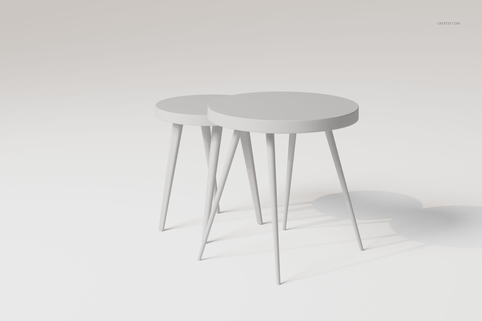 Two round nesting tables with sleek, angled legs in a minimalist light gray setting, shown from a front angle.