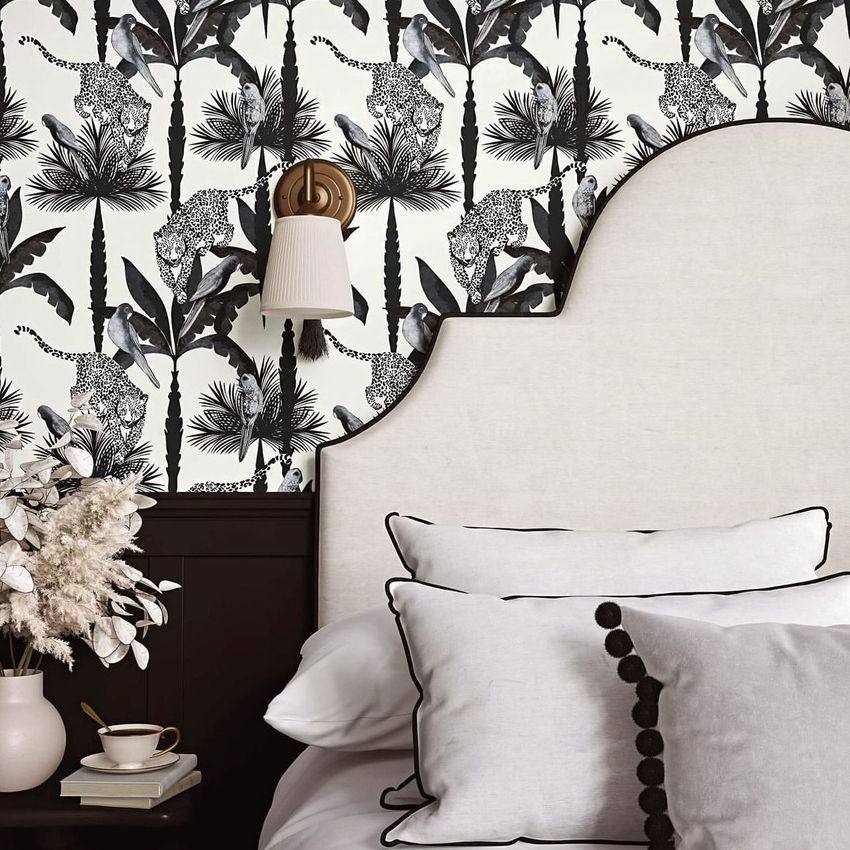 Bedroom pillows, a curved upholstered headboard, and black and white botanical wallpaper with animal motifs in a styled interior mockup.