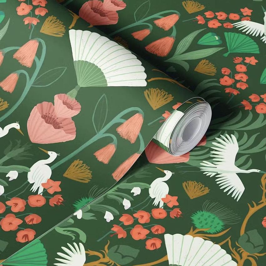 Paper wallpaper mockup featuring a green background with white herons, pink flowers, and large fan-shaped leaves in a rolled layout.
