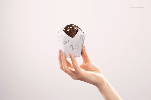 PSD mockup showing a pastry shop muffin wrapped in printed white food paper, presented in a minimalist scene.
