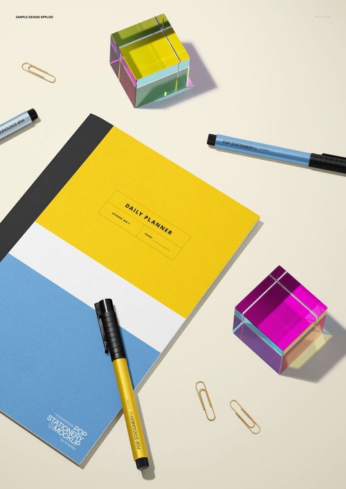 Notebook mockup featuring a daily planner with colorful acrylic cubes, black pens, and gold paper clips on a beige background.