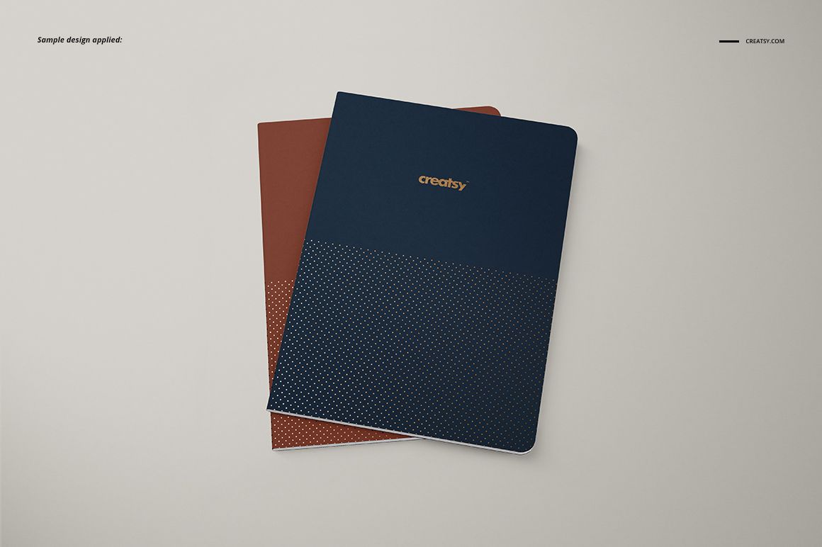 A5 notebook PSD mockup featuring a navy blue notebook with gold text and a brown notebook underneath.