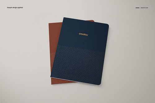 A5 notebook PSD mockup featuring a navy blue notebook with gold text and a brown notebook underneath.