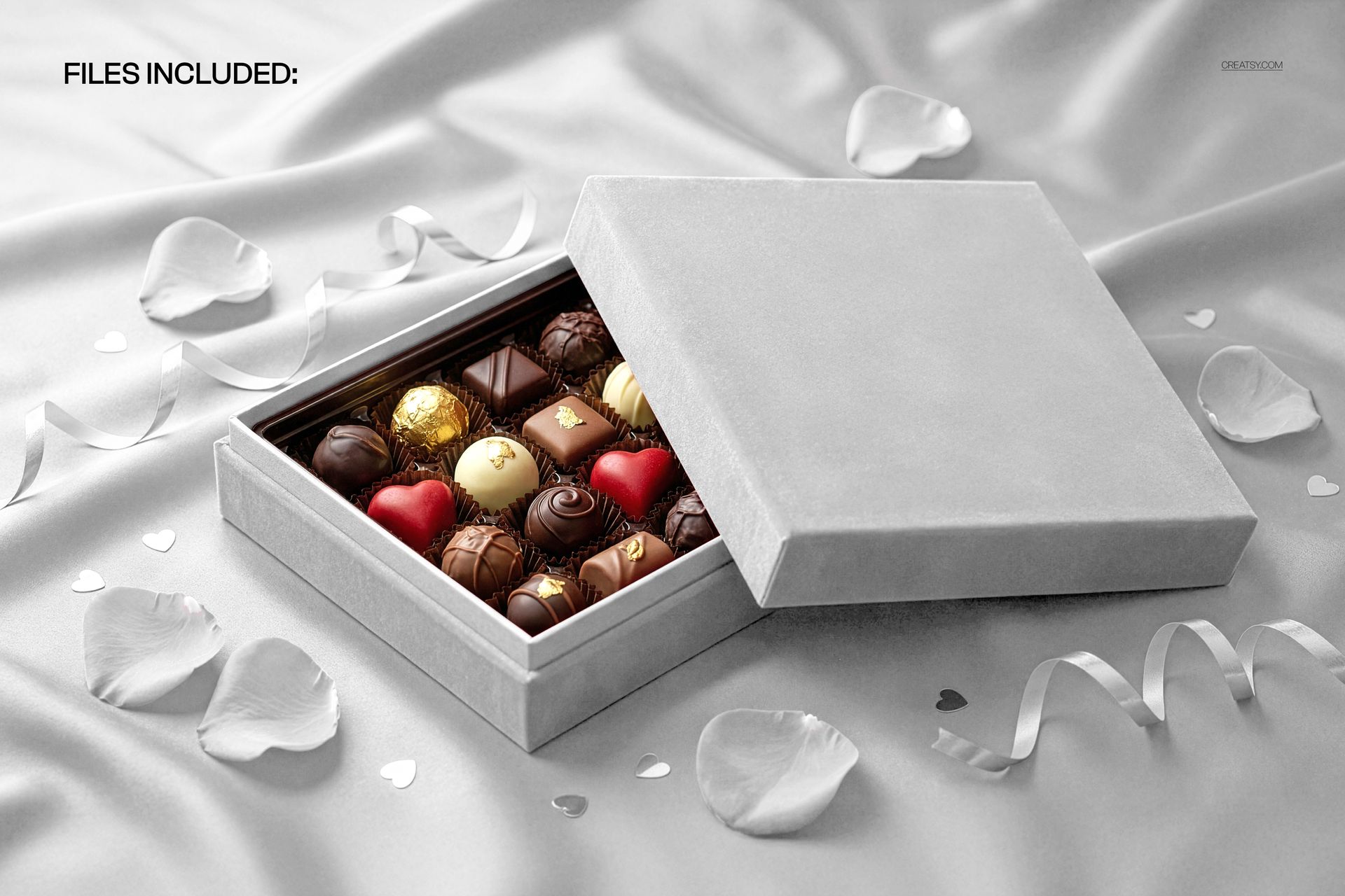 PSD mockup of a praline box filled with chocolates, placed on smooth gray velvet with decorative petals and ribbons.