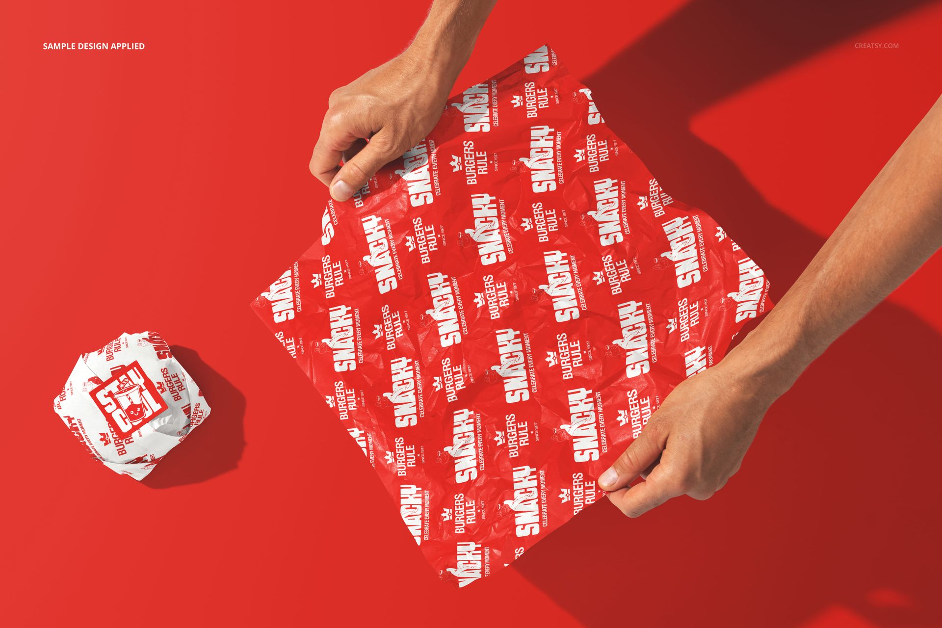 Burger wrapping paper mockup featuring a vivid red and white design, shown flat and wrapped, top view with hands.