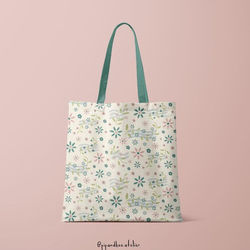 Tote bag mockup featuring a cream-colored bag with a pastel floral pattern, shown upright against a soft pink background.