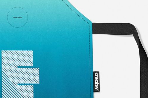 Close-up of a blue apron mockup featuring a white dotted design, black neck strap, and creatsy tag detail.