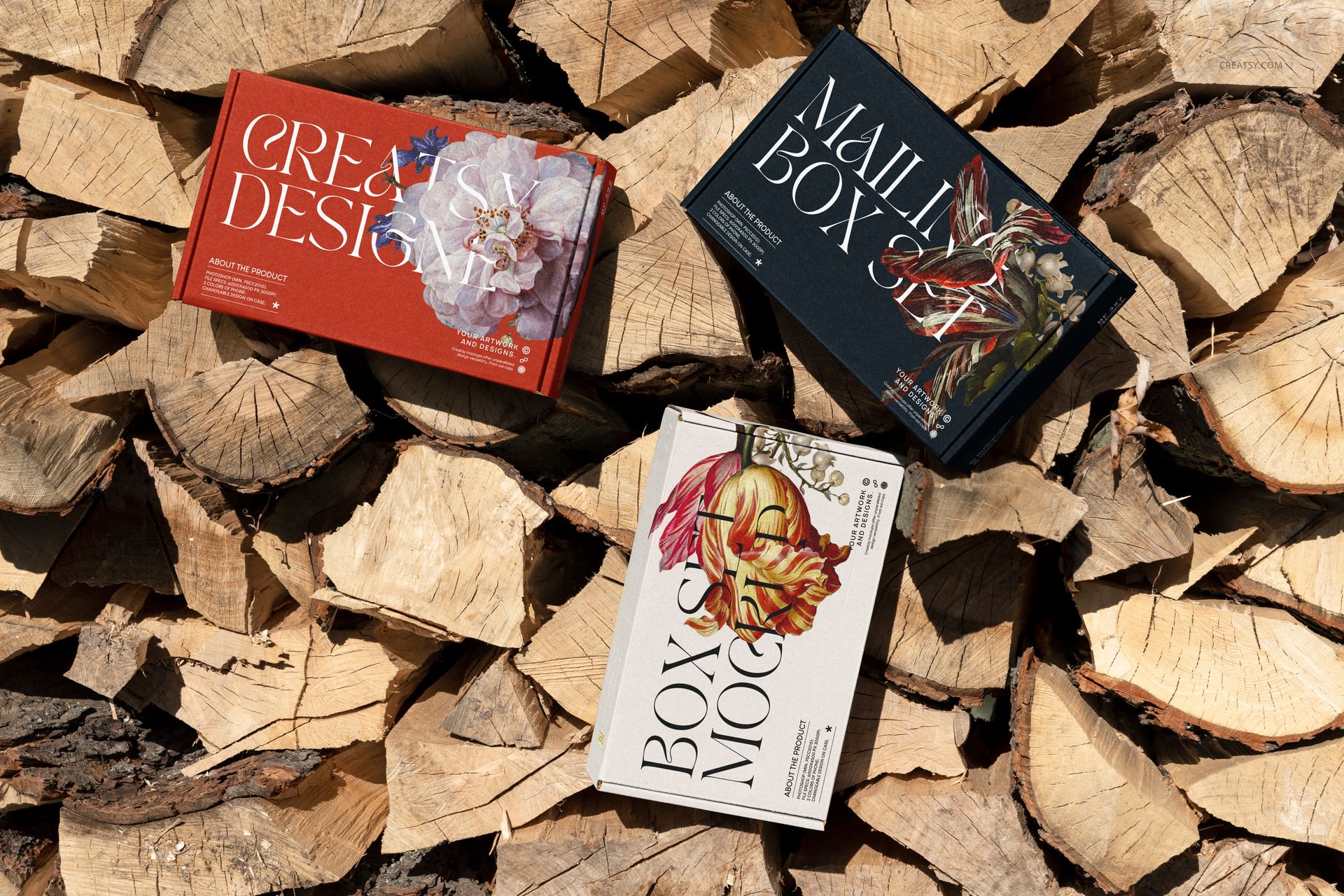 Set of three mailing box mockups with artistic flower graphics, displayed on a pile of split firewood in sunlight.