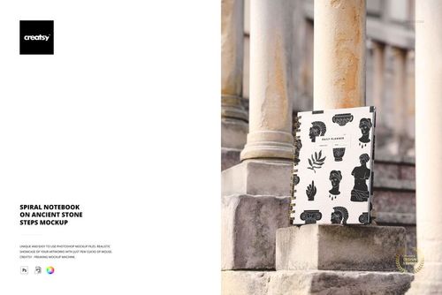 PSD mockup showing a spiral notebook with monochrome design, positioned on old stone steps next to decorative pillars.