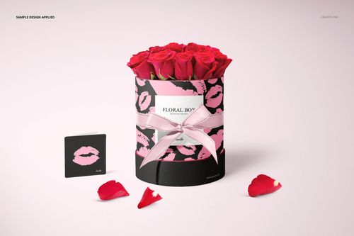 PSD mockup of a cylindrical floral box decorated with pink kiss prints, containing red roses, with scattered petals.