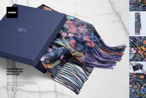 Woven fringed scarf with colorful floral pattern partially pulled from a blue gift box, displayed on marble surface.