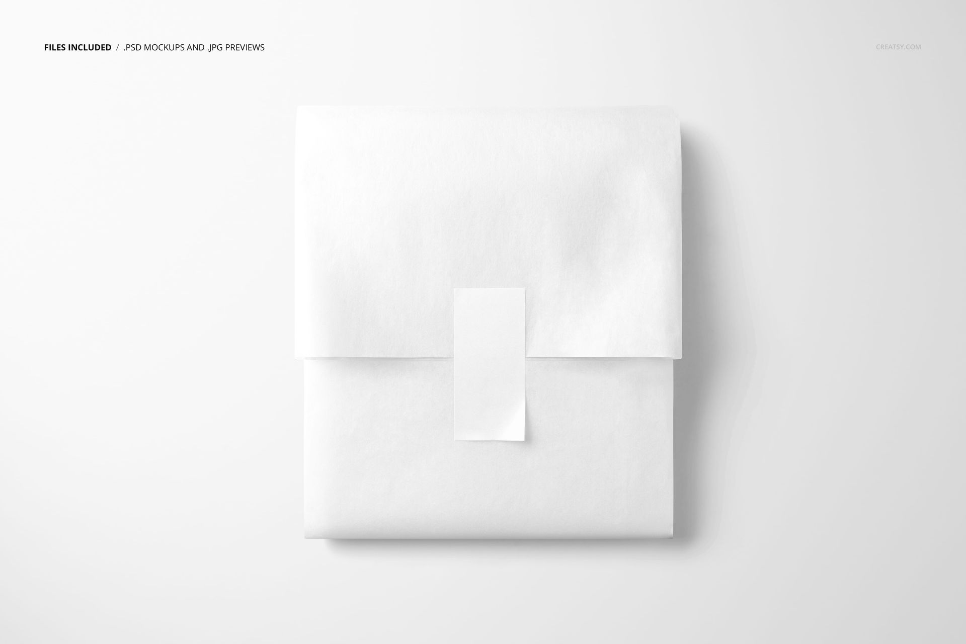 PSD mockup featuring folded white tissue paper secured by a vertical sticker, placed on a minimal white backdrop.