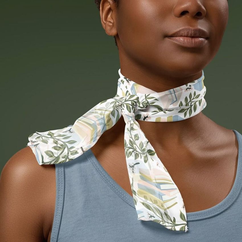 Chiffon silk neck scarf mockup featuring a leafy print, tied around the neck of a model in a blue top, with a plain green backdrop.