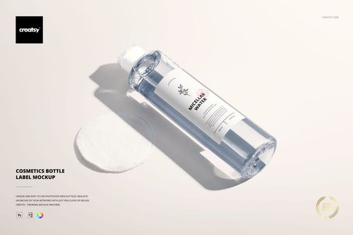 PSD mockup of a transparent cosmetics bottle with a white label, displayed on a soft light surface next to a cotton pad.