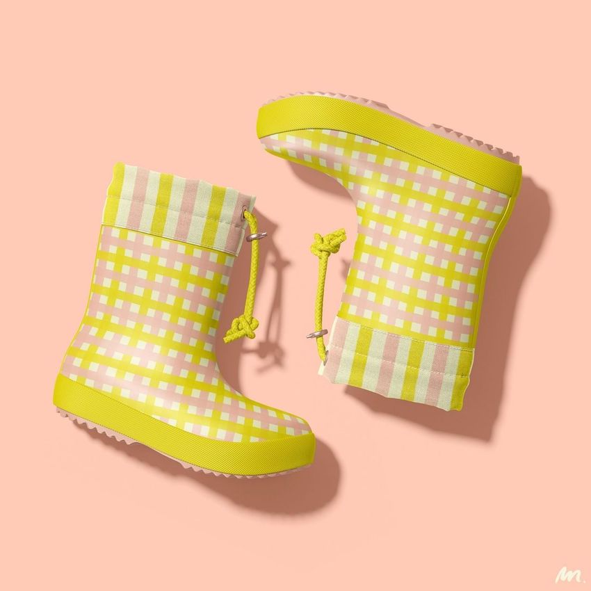 Kids rain boots mockup featuring two boots with a yellow and pink plaid pattern on a pastel pink background, shown from above.