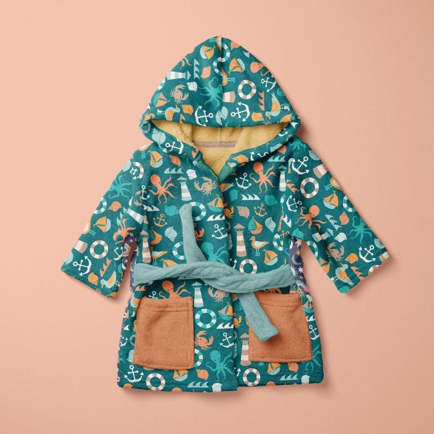 Kids bath dressing gown mockup featuring a sea creatures pattern in teal, orange, and white on a peach background.