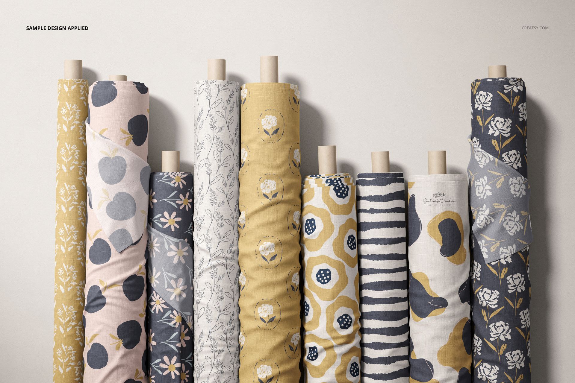 Fabric rolls mockup with diverse patterns including flowers and stripes, shown from the front against a neutral background.