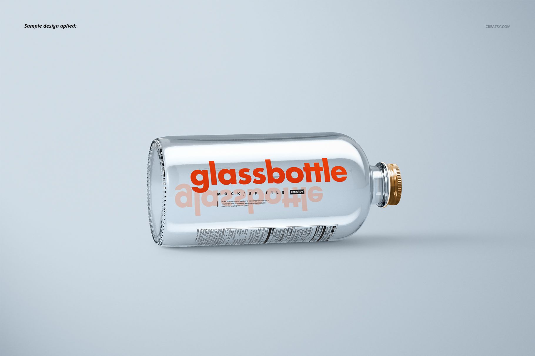 Horizontal mockup of a transparent glass bottle with metallic cap and orange lettering, set against a plain background.