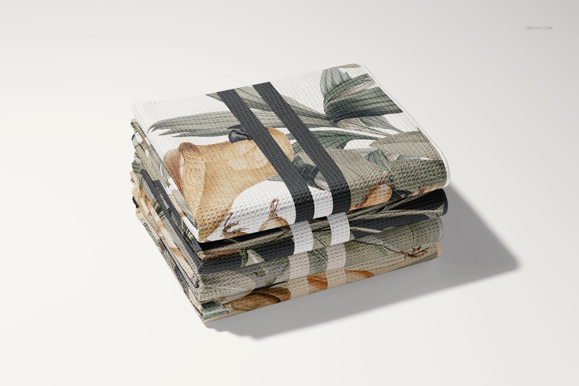 PSD mockup of stacked beach towels with a nature-inspired print, photographed on a clean, light background.