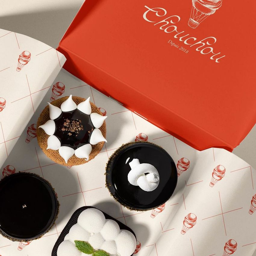 Food safe paper mockup featuring three assorted desserts placed on patterned wrapping paper inside an open red box.