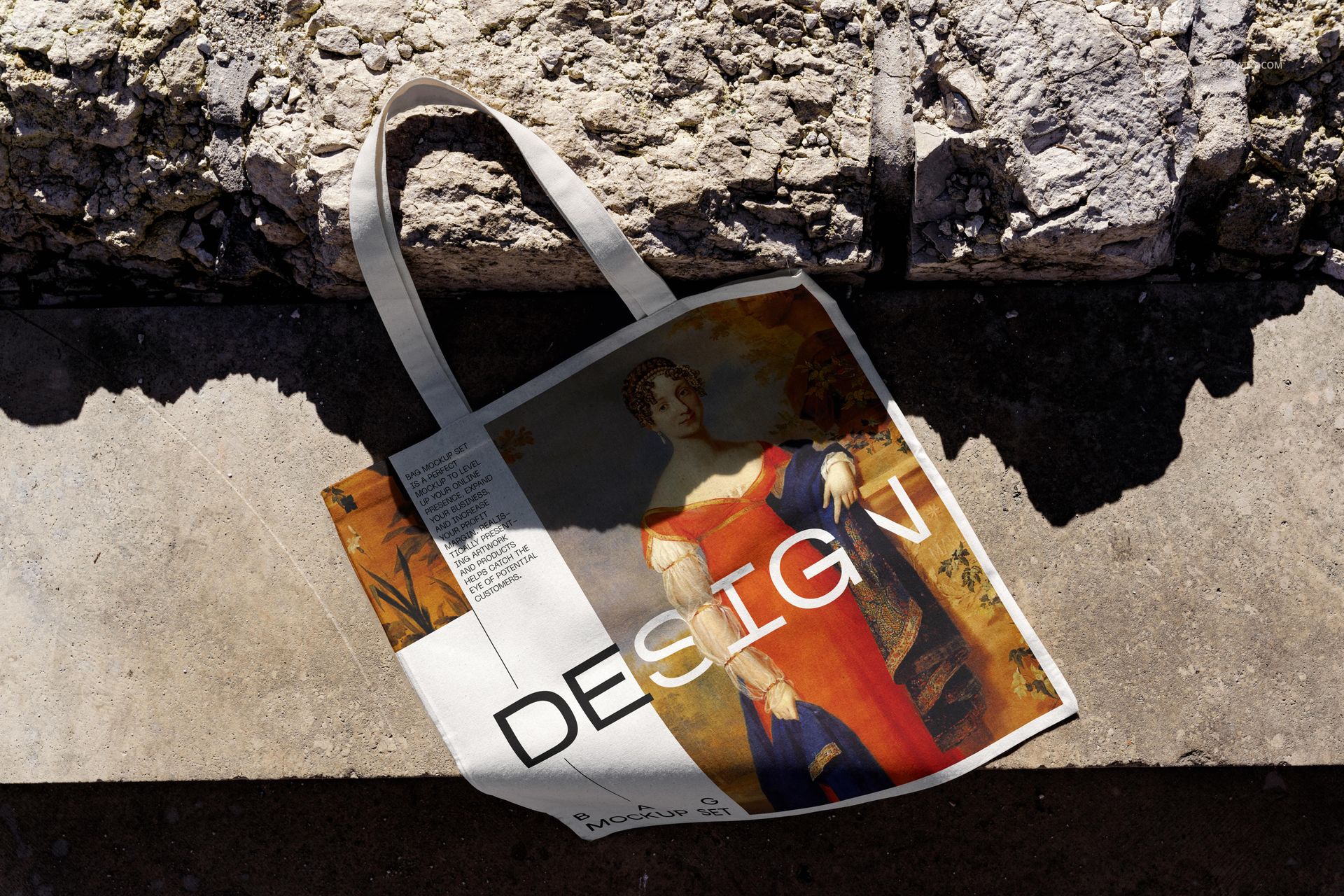 Canvas tote bag mockup with artistic print and text, lying on outdoor stone surface in natural sunlight.