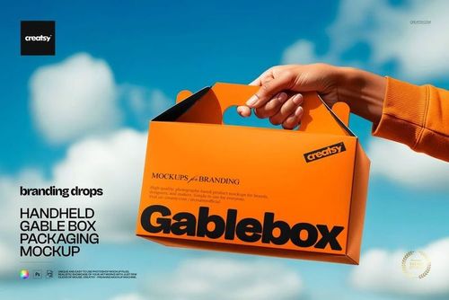 Orange handheld gable box mockup shown outdoors, with a clear blue sky and white clouds in the background.