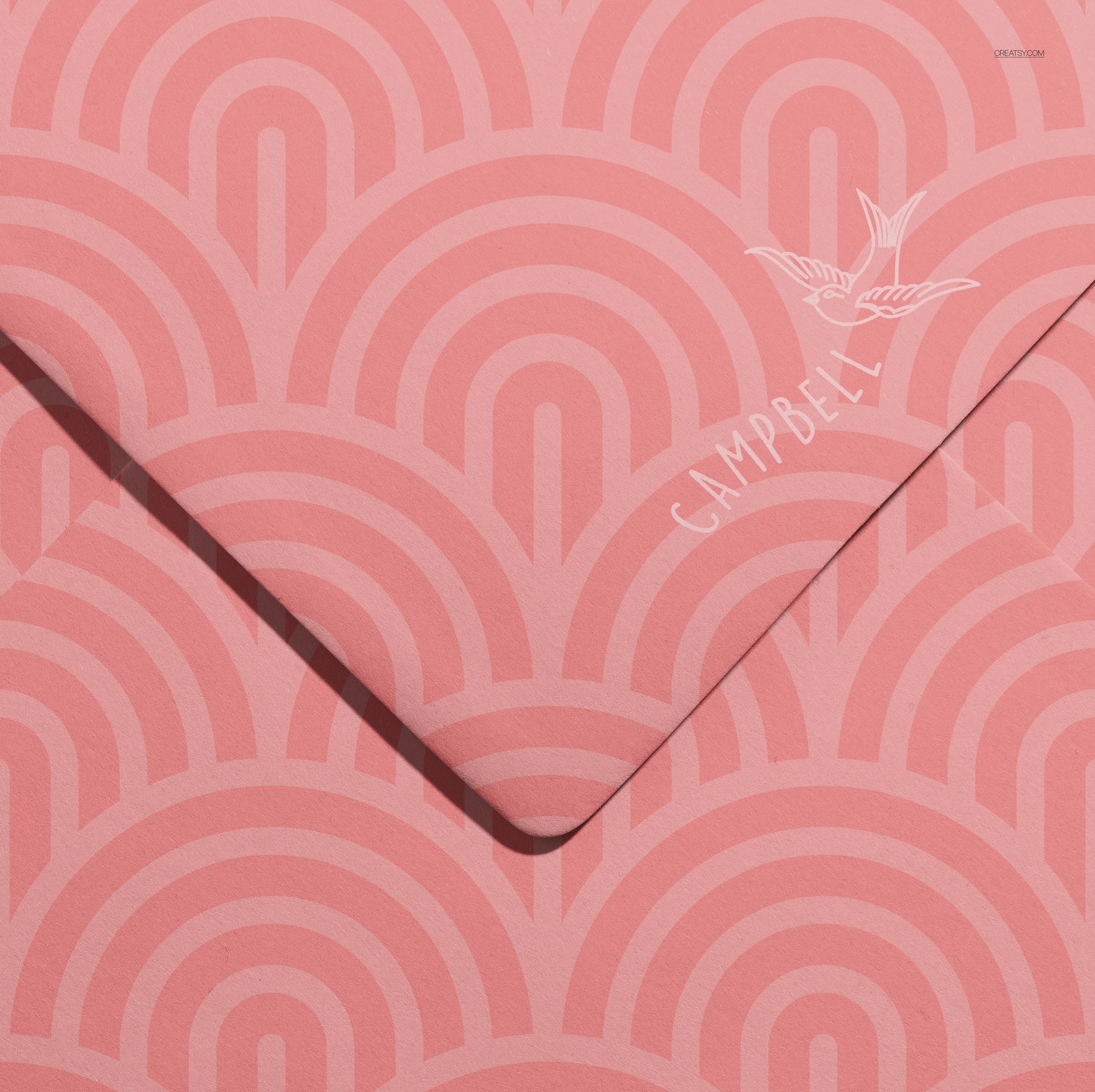 Top view of a stationery envelope mockup featuring pink tones and repeating semi-circular designs.
