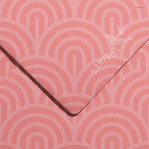 Top view of a stationery envelope mockup featuring pink tones and repeating semi-circular designs.