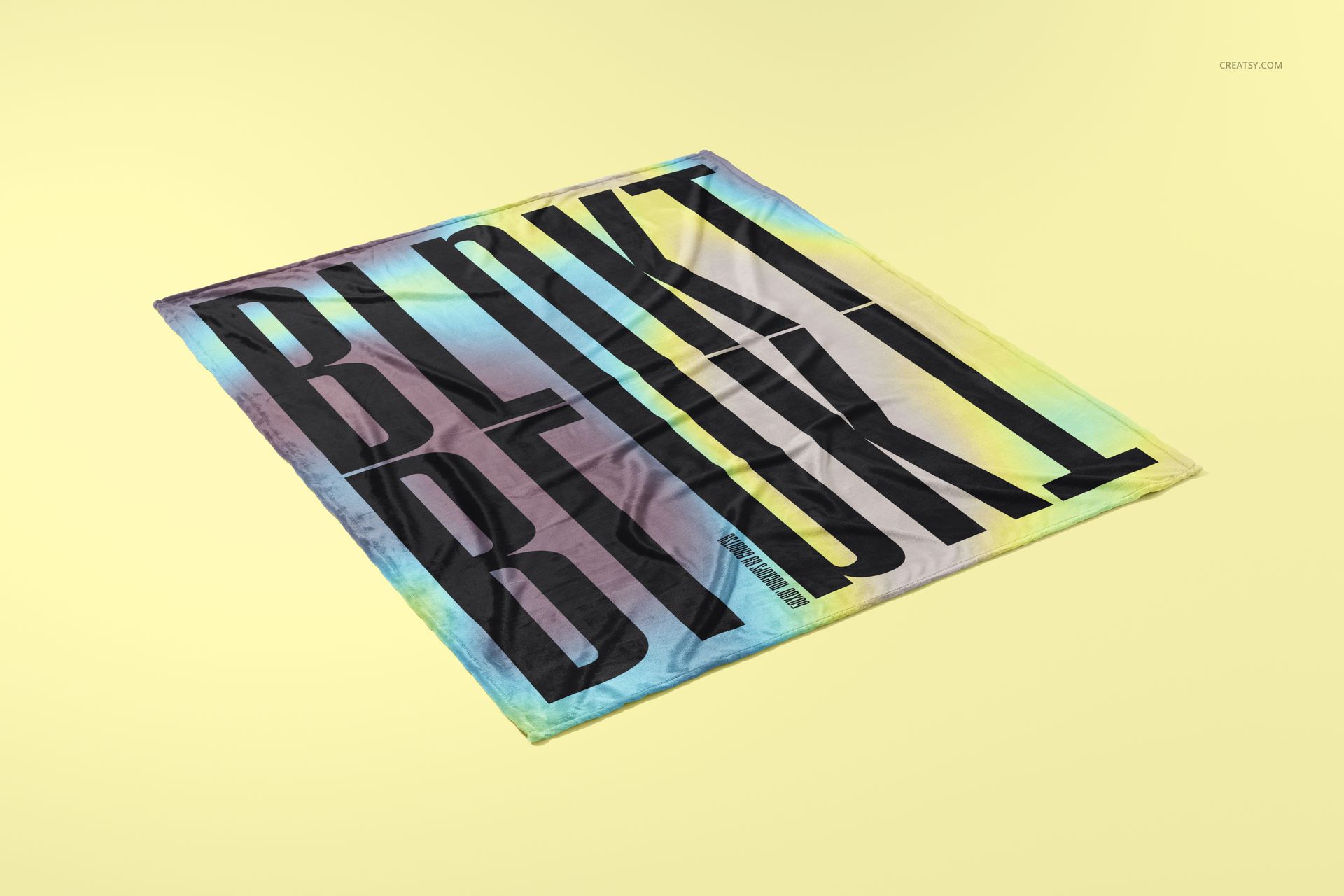Fleece blanket mockup featuring a square blanket with a bold black text design on a gradient yellow background, angled view.
