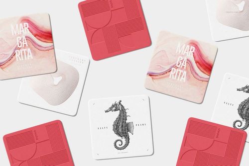Scattered square coasters mockup set showing geometric shapes, wavy lines, and cocktail-themed artwork.