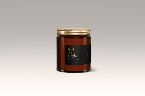 Front view of an amber jar candle mockup featuring a gold lid and dark label, set against a light gradient backdrop.