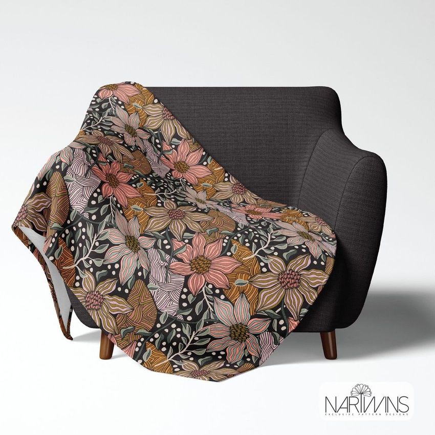 Fleece throw blanket mockup draped over a dark gray armchair, featuring a colorful floral pattern in earthy tones.