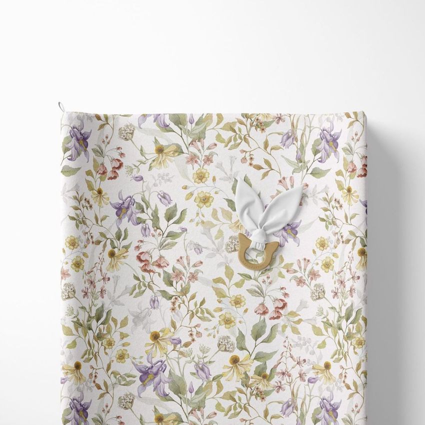 Changing pad mockup featuring a soft white surface with a delicate floral pattern in pastel colors, viewed from above.