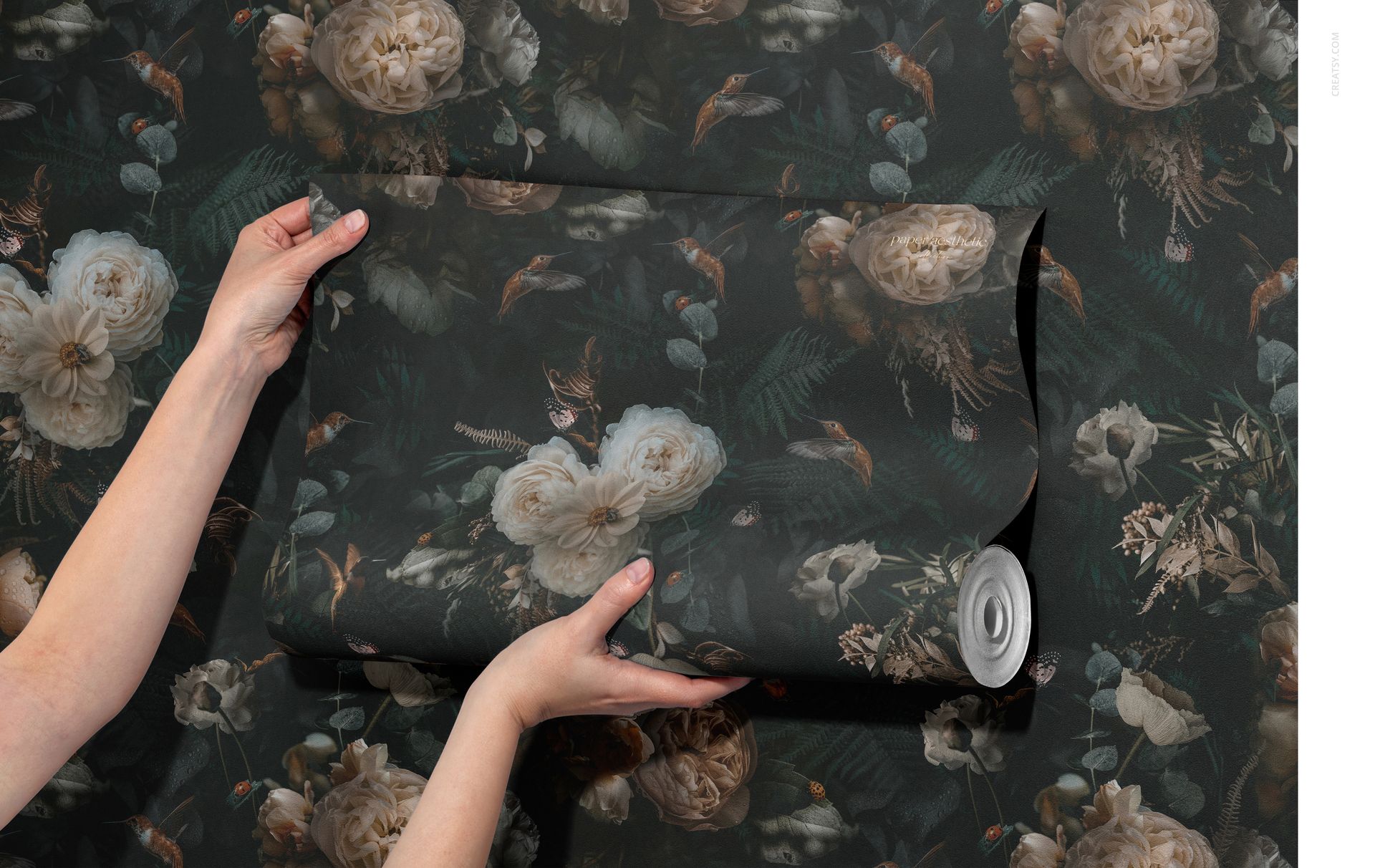Non-woven vinyl wallpaper mockup showing a rolled sheet with a botanical design, held in front of a similarly patterned wall.