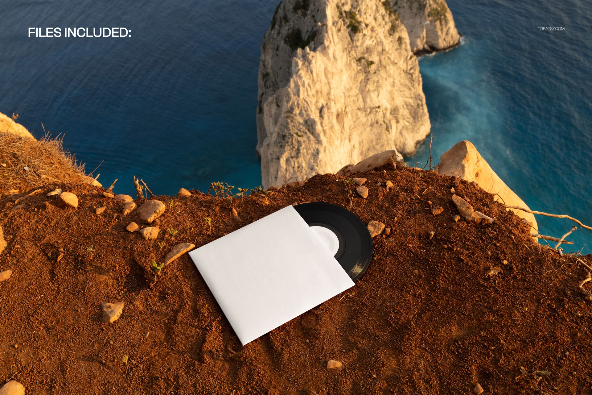 High angle landscape showing a black vinyl record mockup in a white cover on earthy terrain near seaside cliffs.
