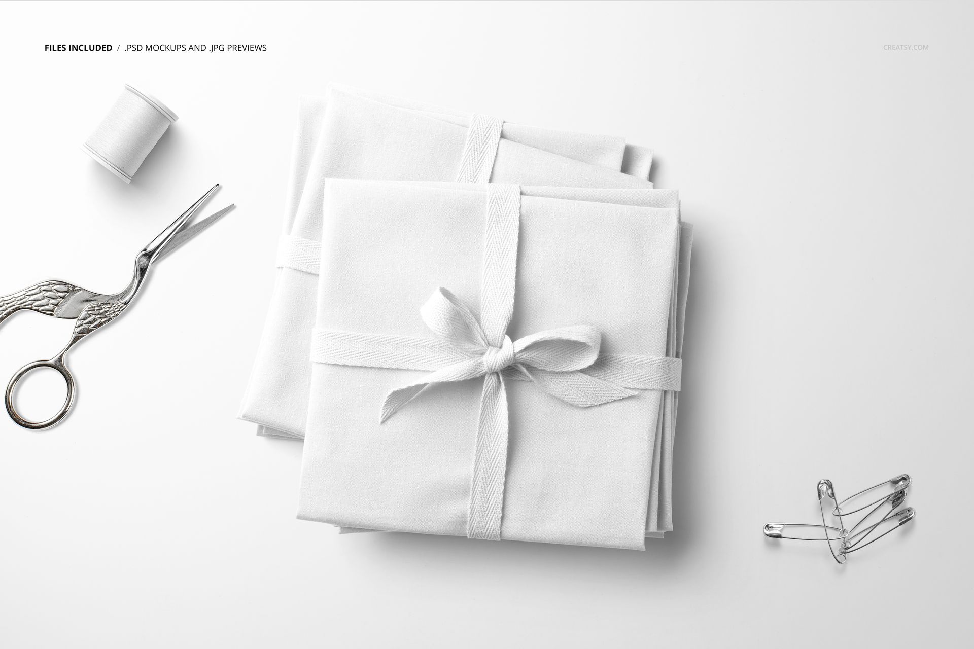Fabric stack mockup featuring folded white textiles with ribbon, displayed alongside sewing accessories on a clean background.