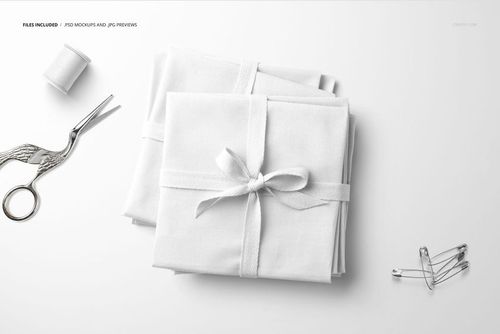 Fabric stack mockup featuring folded white textiles with ribbon, displayed alongside sewing accessories on a clean background.