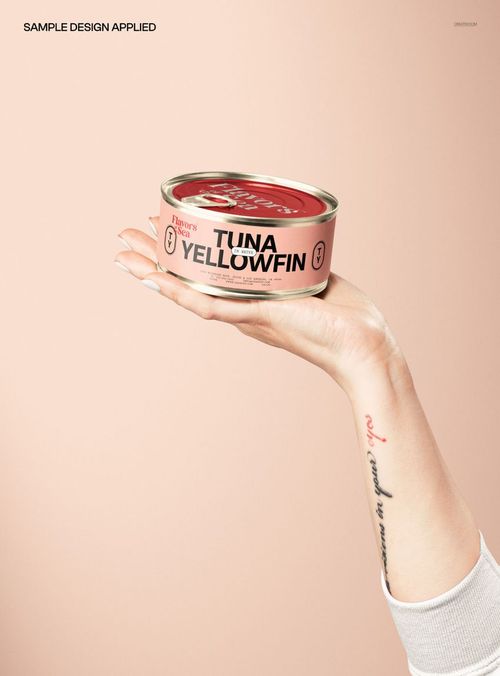 Round, low-profile tin can mockup featuring a pink label, displayed in a hand with visible tattoo and nail polish.