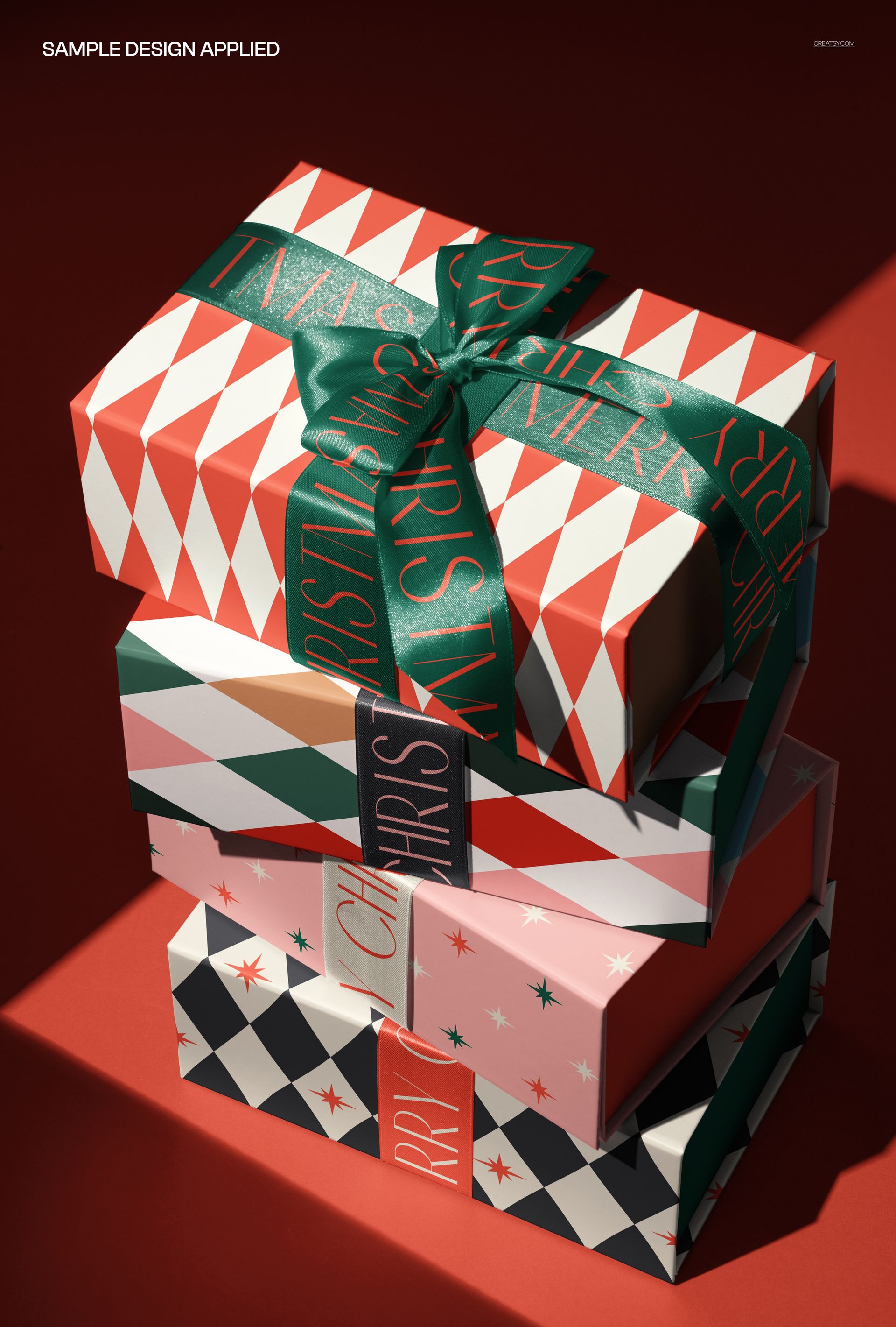 PSD mockup of packaging boxes stacked on a red surface, decorated with festive satin ribbon and various patterns.