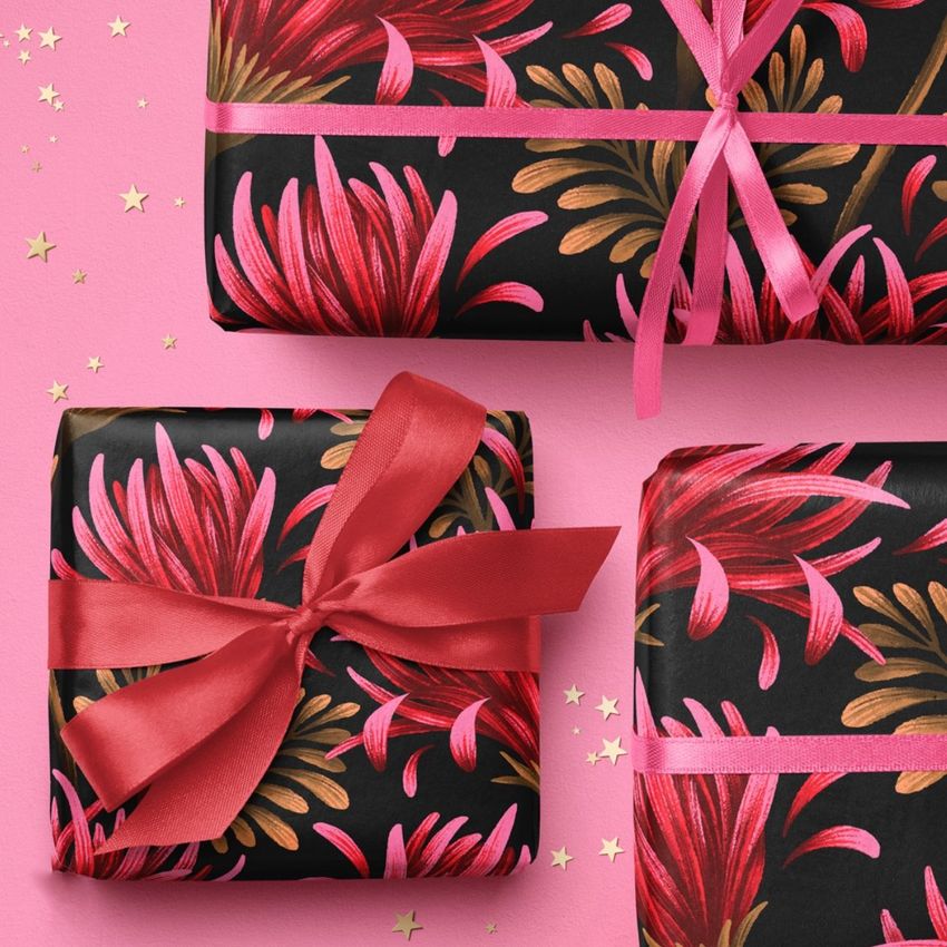 Christmas wrapped gifts mockup featuring three presents with red and gold floral patterns on black paper, tied with pink and red ribbons.