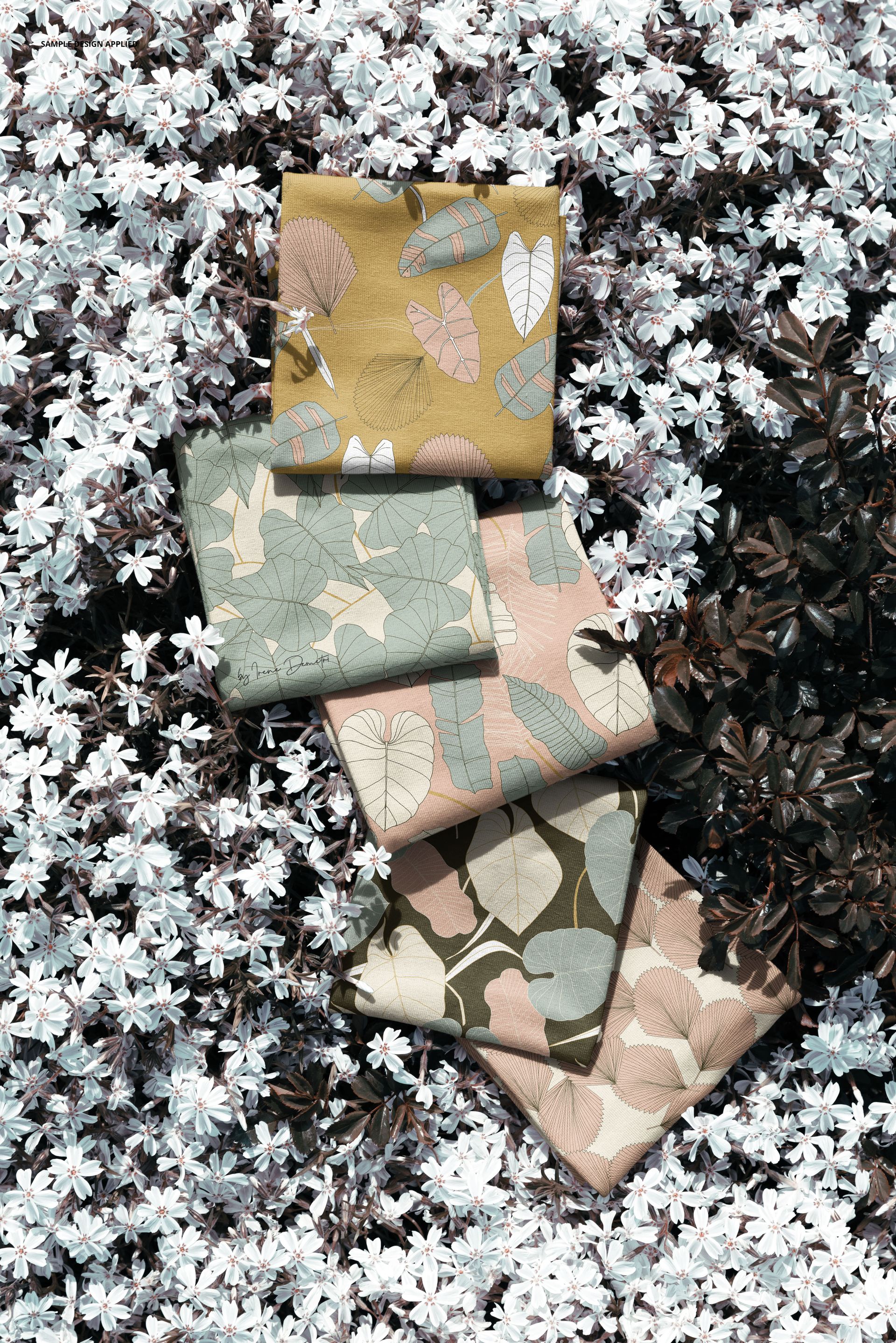 PSD mockup featuring fabric swatches with various leaf motifs placed atop a cluster of small white blossoms.