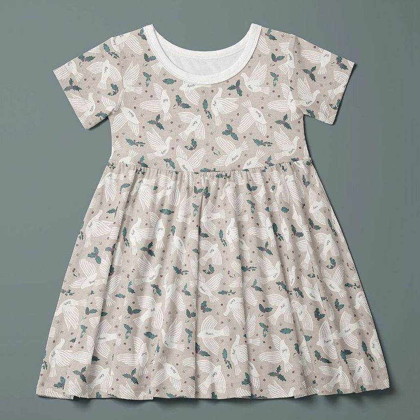 Toddler skater dress mockup displayed flat against a muted green background, featuring a whimsical animal and leaf pattern in soft tones.