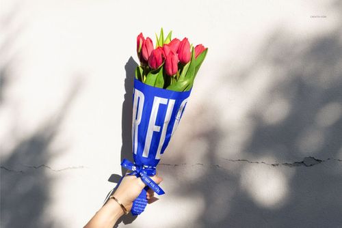 PSD mockup showing a tulip bouquet in blue and white tissue wrapping, with shadows cast on a neutral background.