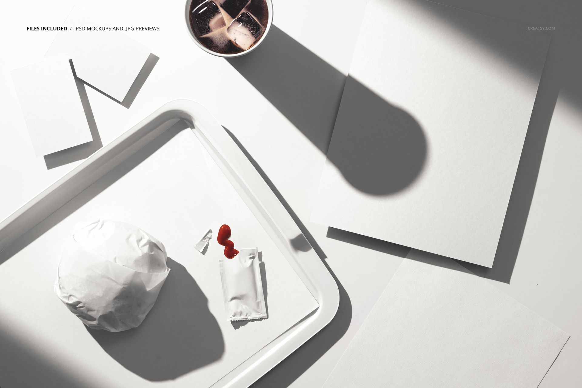 Fast food tray mockup featuring a wrapped sandwich, condiment packets, blank flyers, and a beverage cup in sunlight.