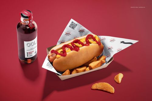 Hot dog mockup featuring a paper tray lined with branded food safe paper, potato wedges, and a cola bottle on red background.