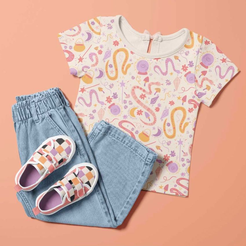 Kids t-shirt and jeans mockup featuring a patterned short-sleeve shirt with pastel designs and light blue denim pants on a peach background.