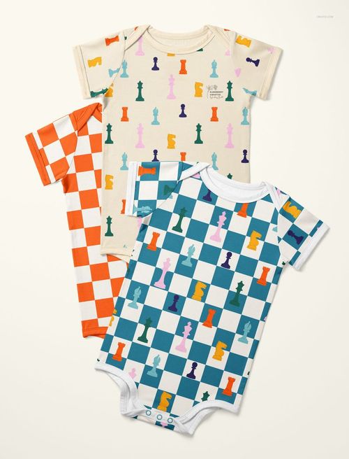 PSD mockup showing three short-sleeve baby bodysuits with multicolor chess and checkerboard prints, laid flat.