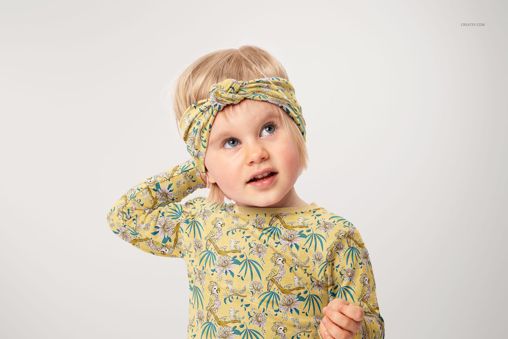 Kids twist knot headband mockup featuring a vibrant yellow pattern, shown on a child against a light background.