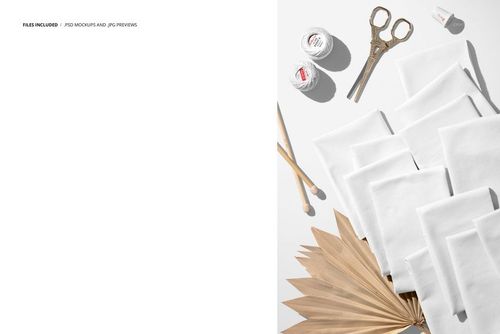 PSD mockup featuring white jersey fabric pieces, crochet threads, scissors, and a dried palm leaf arranged in a creative scene.