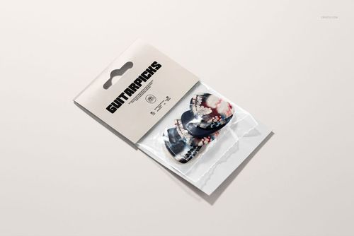 Front view of a guitar pick packaging mockup with two patterned picks in a clear plastic pouch and a beige header card.